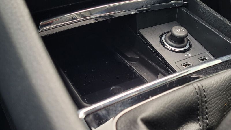 3. Die Smartphone-Lademöglichkeit: Dass es eine Schale zum induktiven Laden gibt, ist positiv. Die Konstruktion ist jedoch verbesserungswürdig. Die Ladeschale befindet sich unter einer aufschiebbaren Abdeckung, was generell eine gute Idee ist. So kommt man gar nicht auf die Idee, das Telefon beim fahren in die Hand zu nehmen. Das Reinlegen und Rausnehmen ist jedoch fummelig, vor allem wenn das Telefon zu den Größeren seiner Art gehört. (Bild: Wehner – VCG)