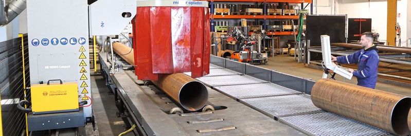 Über einen 16 Meter langen Rollgang-Förderer werden die außerhalb der Halle gelagerten Rohre bis 8.000 Kilo Stückgewicht der Schneidanlage zugeführt. Der vollautomatisierte Schneidtisch der Anlage besitzt 12 höhenverstellbare Rohrunterstützungen, die sich automatisch der zum Teil unrunden Rohroberfläche anpassen und so für eine perfekte Auflage über die gesamte Rohrlänge sorgen.(Bild:  Müller Opladen)
