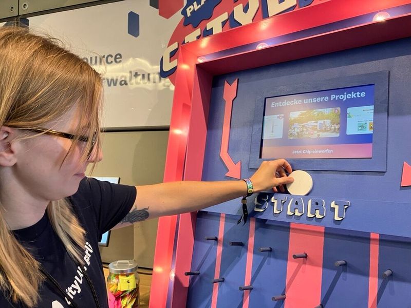 Mit vielen spielerischen Elementen konnten Besucherinnen und Besucher den Themen auf der Veranstaltung näherkommen – zum Lernen und Ausprobieren. Beim „CityLAB Plinko“ im Foyer wirft man einen Chip ins Board. Je nachdem, wo er landet, wartet entweder ein spannendes Projekt – oder das Impuls-Los als kleiner Gewinn. Auf diese Weise wird spielerisch gezeigt, woran das CityLAB Berlin aktuell arbeitet.  (Bild: Serina Sonsalla / Vogel IT-Medien)