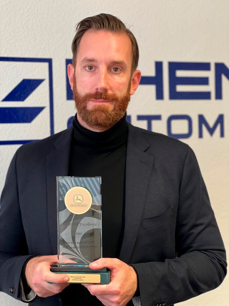 Thomas Bernhardt, der Geschäftsführende Direktor und COO von Rhenus Automotive, hält einen der jüngst verliehenen John-Deere-Awards nicht ohne Stolz in den Händen.