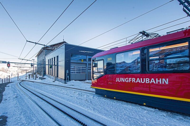 Blick auf die Tore der Werkstatt, während ein Niederflurtriebzug der Jungfraubahn an der Station Eigergletscher durchfährt. Die bisherige Taktzeit wurde von  2 auf 1,5 Stunden reduziert. (Thomas Entzeroth)