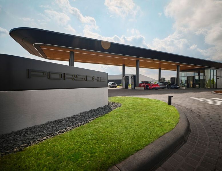 In dem Gewerbegebiet bei Bingen am Autobahndreieck Nahetal (A60/A61) fällt die Porsche Charging Lounge direkt ins Auge. Das abgerundete Dach sieht aus wie eine Flugzeugtragfläche, die von runden Pfeilern gehalten wird. Die Sitzgelegenheiten aus hellem Holz an den Schnellladern sind abgerundet und auch die raumhoch verglaste Lounge hat keine Ecken.  (Bild: Porsche)