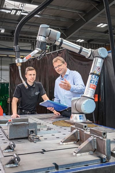 Maximal zufrieden mit der Cobot-Lösung von Lorch und den Vorzügen des neuen UR10e: Jürgen und Nils Tippe (v.r.n.l.) Betriebsleiter und Schweißaufsicht bei der Jorado Maschinenbau GmbH in Lüneburg.  (Bild: Lorch)