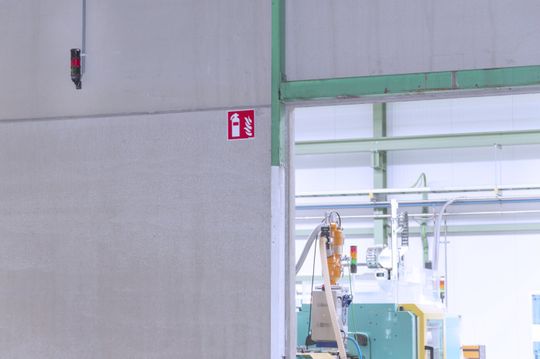 (Bislang problematisch: Die Betonwand zwischen den beiden Produktionshallen stellte ein Hindernis bei der Erkennung von Maschinenstörungen dar. Dank einem zusätzlich angebrachten „Repeater“ können die Signale nun einwandfrei übertragen werden.  Bild: Werma)