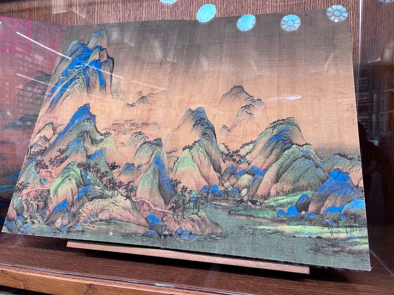 Abbildung 45: Im Original hat das Bild einen unschätzbaren Wert. Es stammt von Wang Ximeng, ein Hofmaler in der Nördlichen Song-Periode, im frühen zwölften Jahrhundert. Im Jahr 1113, im Alter von 18 Jahren, schuf er sein einziges erhaltenes Werk, eine lange blaugrüne Schriftrolle mit dem Titel „Tausend Li von Flüssen und Bergen“. Er starb im Alter von 23 Jahren.  Das Gemälde wird seitdem als ein Meisterwerk der chinesischen Kunst bezeichnet; die Schriftrolle befindet sich in der ständigen Sammlung des Palastmuseums in Peking. Die Landschaft auf dem Gemälde wurde später als der Berg Lu und der Poyang-See in Jiujiang identifiziert. (Bild: uo/ Vogel IT-Medien GmbH)
