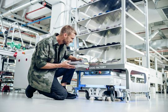 Ein Mitarbeiter von Engelbert Strauss begutachtet einen Schuh vor einem Schuhrondel in der CI Factory in Schlüchtern.(Bild:  engelbert strauss GmbH & Co. KG)