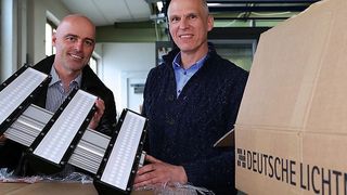 Die neuen dreiflammigen LED-Hallendeckenstrahler werden ausgepackt: Roman Teufl, Geschäftsführer Vertriebsgesellschaft Deutsche-Lichtmiete-Unternehmensgruppe, und Peter Andrä, Geschäftsführender Gesellschafter Riedl Aufzugbau GmbH & Co. KG. (Bild: Deutsche Lichtmiete)