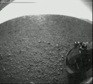 Erste Bilder, die Curiosity nach seiner erfolgreichen Lan-dung auf den Mars an die Erde gesendet hat. Auf dem Bild erkennt man eins der insgesamt sechs Räder des Marsrovers. (NASA, JPL-Caltech)