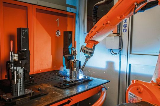 Mithilfe des Schweißgeräts verbindet der Roboter das achteckige Prisma mit der kompakten Platte aus Stahl. Nach 90 Sekunden sind zwei Schweißvorgänge abgeschlossen.(Bild:  Kuka)
