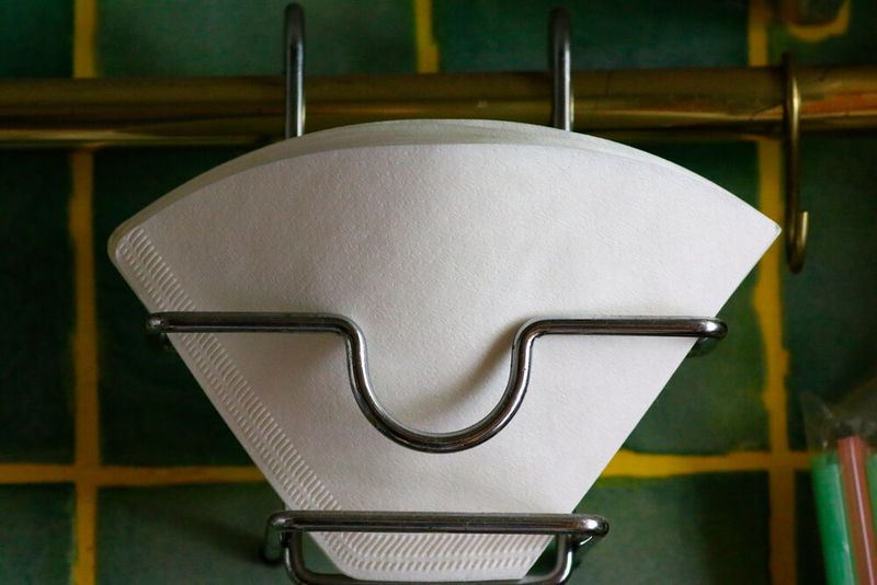 Lästiger Kaffeesatz im Kaffee hat Melitta Benz auf die Idee des Kaffeefilters gebracht: Ein Messingtopf, in dessen Boden sie Löcher mit Hammer und Nagel geschlagen hatte, und ein zurechtgeschnittenes Löschblatt aus dem Schulheft ihres Sohnes war der erste Kaffeefilter. 1908  meldete sie ein Patent für einen „Kaffeefilter mit auf der Unterseite gewölbtem und mit Vertiefung versehenem Boden sowie mit schräg gerichteten Durchflusslöchern“ an. (Bild: gemeinfrei)