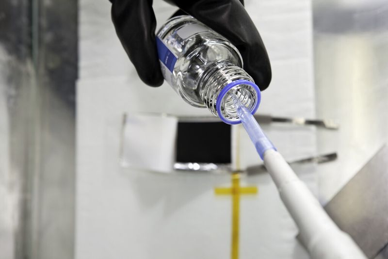 Ein Chemielaborant füllt in einer Glove-box optimierte Elektrolyte in eine Lithium-Testbatterie. (Bild: BASF)