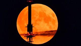 Der rötlich schimmernde Vollmond leuchtet am Abendhimmel hinter einem Funkmast. Wie Nokia meldet ist der finnische Mobilfunkausrüster von der US-Raumfahrtbehörde Nasa auserkoren worden, ein Mobilfunknetz auf dem Mond aufzubauen. (Bild: Patrick Pleul/dpa)