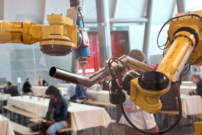Der mit dem YLR-Faserlaser bestückte Bearbeitungsroboter demonstriert dann simulatorisch die Einarbeitung von 3D-Rohrausschnitten, während der andere Roboter das Werkstück fest hält. (Königsreuther)