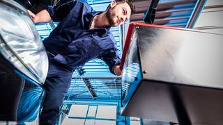 Ein Mitarbeiter eines Kfz-Betriebs überprüft beim Licht-Test die Beleuchtung eines Fahrzeugs.  (Bild: ProMotor)