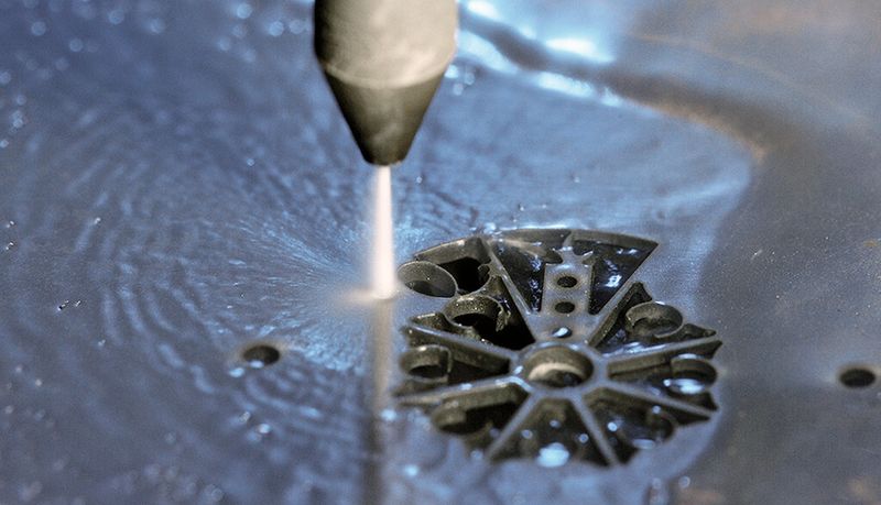 Hier sieht man, wie das Bauteil aus dem Blech herausgeschnitten wird. Auf der nächsten Seite das fertige Bauteil (Waterjet)