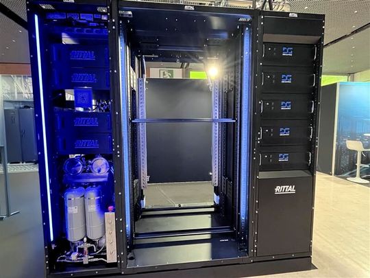 Das ist die Umsetzung der OCP-„Open Data Center“-Überlegungen von Rittal: In der Mitte ein Rack doppelter Breite, allerdings hier ohne die OCP-typische Stromschiene im Rack (Bas Bar), zu sehen. Links daneben befindet sich die CDU und rechts ist ein Power-Sidecar, das Rittal zusammen mit Siemens Smart Infrastructure entwickelt hat, um die Spannung von ±400 Volt DC auf 48 V DC zu wandeln, die normalerweise im Rack benötigt wird.  DC steht hier für Direct Current, Gleichstrom. (Bild:  uo/Vogel IT-Medien GmbH)