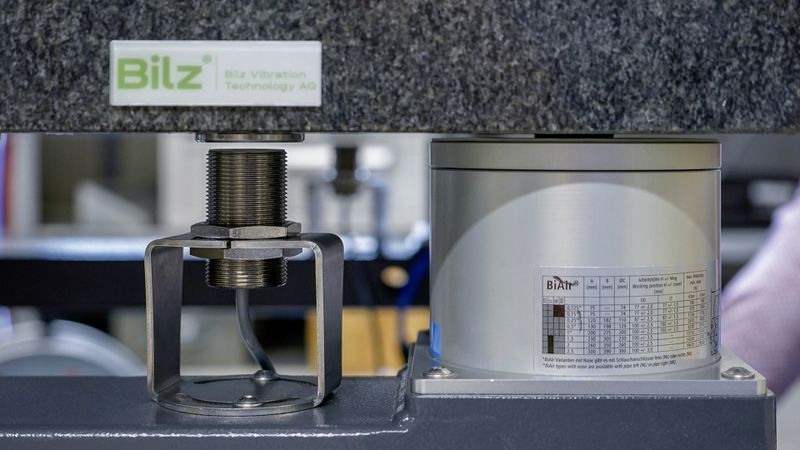 So funktioniert die neue Schwingungsisolation von Bilz: Auf der Granitplatte (oben) steht eine Maschine oder Prüfanlage, die von Schwingungen entkoppelt werden soll. Der induktive Abstandssensor (Mitte) erfasst laufend die Distanz zur Granitplatte (Target ist eine fixierte Stahlscheibe). Gefüttert mit diesen Werten regelt die Steuerung schnell und präzise das Niveau der Luftfeder (rechts). (Bild:  Baumer)