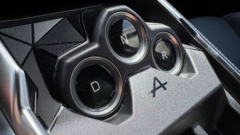 Anders als es bei Renault der Fall ist, wird der Gang nicht über einen Hebel hinter dem Lenkrad eingelegt. Stattdessen gibt es drei Tasten, die auf der Mittelkonsole in einer Pyramide angeordnet sind, eingerahmt von einem Relief aus weiteren Dreiecken. (Bild: Achter – VCG)