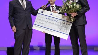 Moderator Oliver Welke verlieht den Preis an Christian Ott, Leiter der Mink-Akademie, und Daniel Zimmermann, Kaufmännischer Leiter des Bürstenherstellers. (Bild: Mink/Jens Schicke)