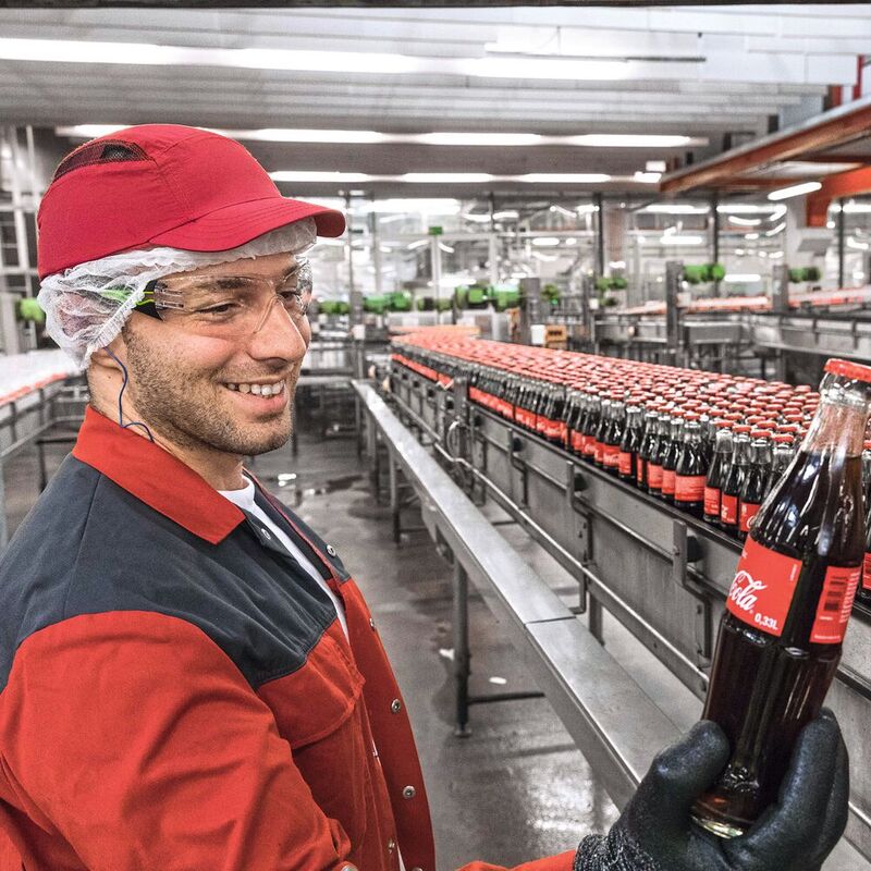 Sichtkontrolle durch einen Mitarbeiter: Blick in die Produktion bei Coca-Cola European Partners Deutschland.