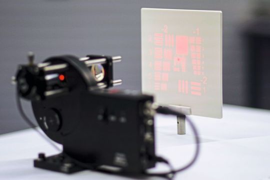 Bild 1: Ein Laserstrahl wird durch ein 3D-gedrucktes diffraktives optisches Element gebeugt. Auf diese Weise entsteht hier das Präzisionsmuster des USAF-Charts. Bild 1: Ein Laserstrahl wird durch ein 3D-gedrucktes diffraktives optisches Element gebeugt. Auf diese Weise entsteht hier das Präzisionsmuster des USAF-Charts.