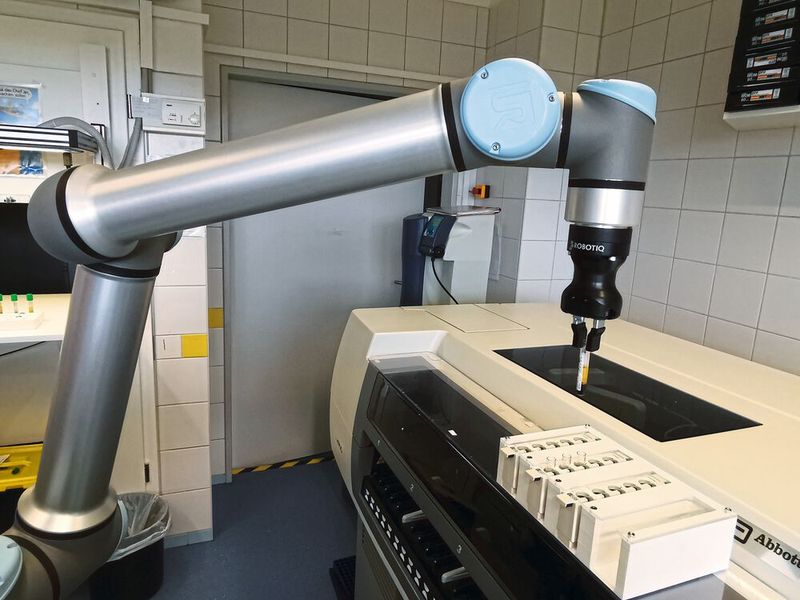The UR10e cobot is seen here placing test tubes containing blood samples into holding devices at Diagnosticum. It then places the devices in the measuring system for analysis.  (Source:UR)