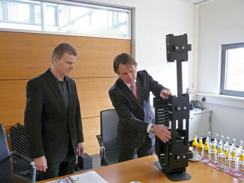 Winkel-GF Thomas Riffert (links) und Igus-Branchenmanager Material Handling Christian Strauch mit einem Modell des Energiekettensystems, das im Colibri-RBG eingesetzt wird. (Bild: Igus)