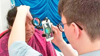 Dr. Maximilian Wintergerst untersucht das Auge einer Patientin mit einer indirekten Smartphone-Lösung (privat/beipress)