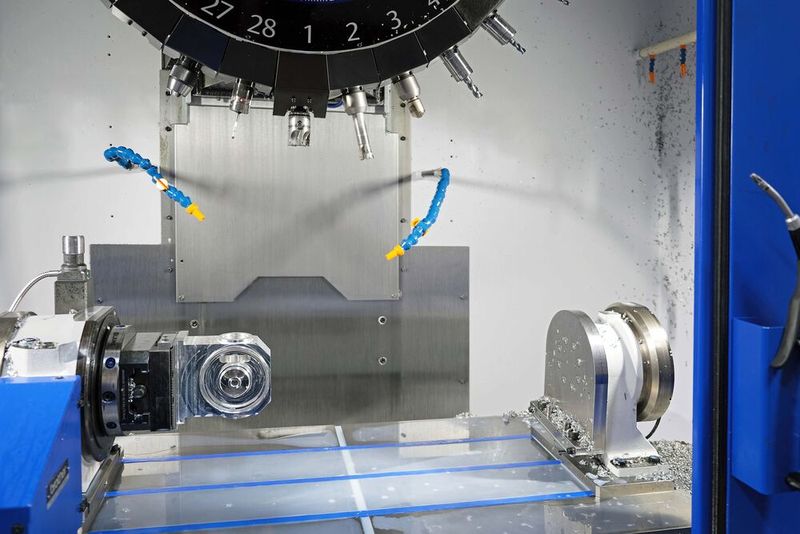 The machine was supplied in a variant with the column raised by 300 mm to accommodate a 4th axis and trunnion arrangement. Here the trunnion has been removed for machining a component mounted directly in the indexing head.  (Source: Whitehouse Machine Tools )