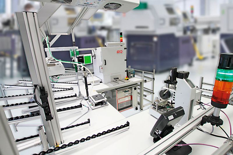 Im Vordergrund rechts die Handpresse für die Montage der Panels, in der Mitte die Station für die Endmontage des Steuergeräts, im Hintergrund die Prüfzelle für die optische und elektrische Prüfung. (MCD Elektronik)