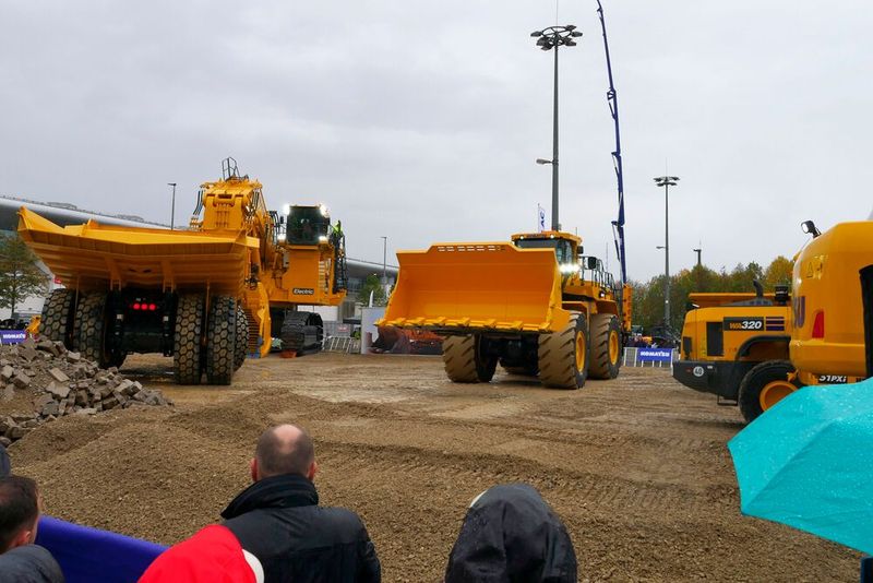 Auf dem Freigelände der Bauma zeigte Komatsu seine großen Maschinen: den Hydraulikbagger PC4000E-11 mit elektrischem Antrieb (hinten links), den Muldenkipper HD785-8 oder den Radlader WA800-8. Trotz strömenden Regen ließen es sich am Montag die Zuschauer nicht entgehen, diese Baumaschinen bei der Live-Demo zu erleben. (Bild: Sandro Kipar/VCG)