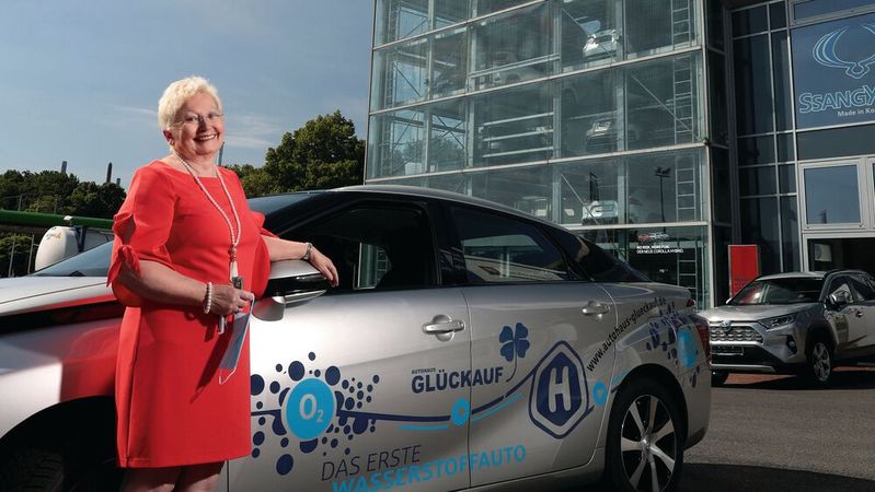 Dietlinde Stüben-Endres vor ihrem Autohaus Glückauf und einem mit H2 betriebenen Toyota.(Bild:  André Chrost - PhotoDesign)
