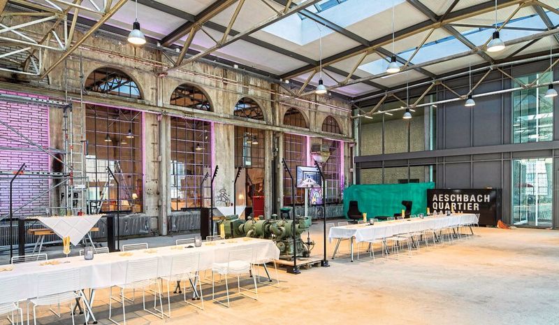 Die Aeschbachhalle bildet das Herz des neuen Quartiers. Wo früher Maschinen montiert wurden, wird seit 2019 gefeiert, gegessen und getrunken. (Bild: Werbebroschüre Aeschbachhalle 2019)