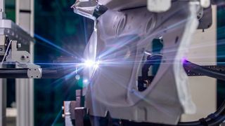 Die Audi AG bevorzugt bei der partiellen Oberflächenreinigung dünner Karosserieteile aus Aluminium das Plasmaverfahren Acerios von Fronius. Hier hat ein Roboter bei Audi ein Bauteil an den fest installierten Plasmabrenner laviert, wo es nun für das Bolzenschweißen vorbehandelt wird. (Fronius)