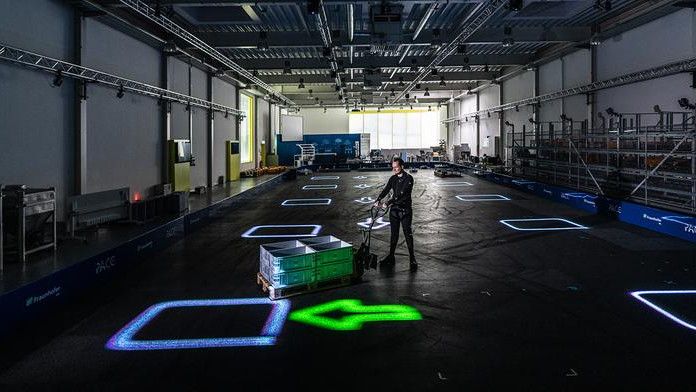 Das dynamische Leitsystem LARS wirft Informationen per Laserprojektion direkt auf den Boden der Lagerhalle. (Bild:  © Fraunhofer IML, Michael Neuhaus)