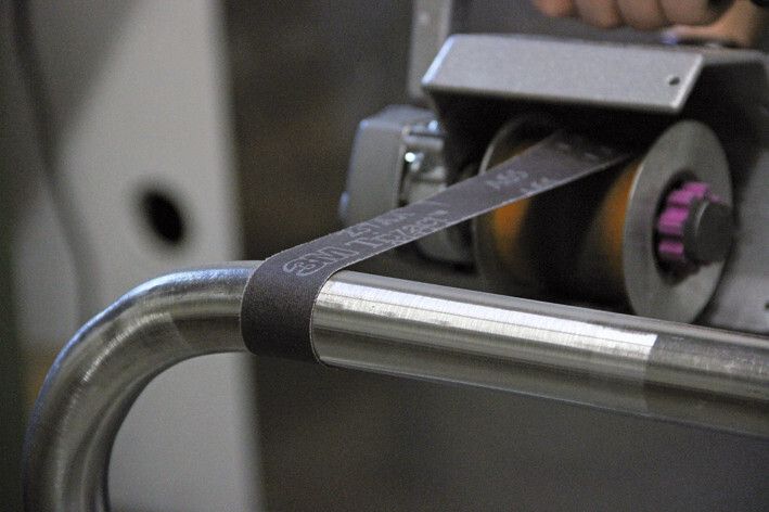 Mit grobem Trizact-Band (Trizact ist ein geschütztes Warenzeichen), je nach Oberfläche entweder mit Körnung A100 oder A65, werden gezielt Kratzer, Schweißnähte und Walzhaut entfernt. Bei geschlossenen Rohrkonstruktionen kann das Schleifband mit Klebeband wieder verschlossen werden. (Bild: Eisenblätter)