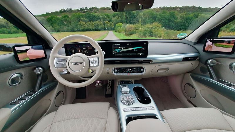 4. Das Cockpit: Ein Hingucker ist das riesige geschwungene Panoramadisplay, das sich fast von der Tür bis über die Mittelkonsole zieht. Dazu gesellt sich ein weiteres Display über der Mittelkonsole, über das sich die Klima-Anlage regeln lässt. Alles in allem hat der GV60 für ein Elektroauto außergewöhnlich viele Knöpfe und Tasten. Im Dunkeln kommt die Ambientebeleuchtung zum Tragen: Dabei hat man die Wahl aus über 60 Farben. (Bild: Mauritz – VCG)