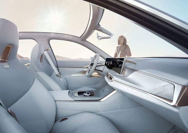 Der aufgeräumte, weiß ausgekleidete Innenraum wird von einem konkaven Curved-Display geprägt, das die analogen Instrumente ersetzt und sich bis über die Mittelkonsole zieht. (BMW)