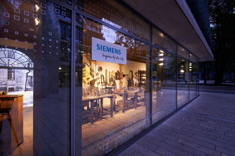 In der neuen Zentrale in München hat Siemens die historische Werkstatt des Firmengründers aus dem Jahr 1847 nachbauen lassen. Die erste Produktionsstätte befand sich in Berlin, im Hinterhaus der Schöneberger Straße 19 im heutigen Bezirk Friedrichshain. Es handelte sich um eine 150 Quadratmeter große Werkstatt, in der zehn Handwerker die ersten Zeigertelegrafen fertigten. Die Geräte wurden an drei Werkbänken aus Weißblech, Kupferdraht, Holzkisten und anderen Materialien hergestellt. Die Werner von Siemens-Werkstatt ist wie ein Schaufenster aufgebaut und öffentlich einsehbar. (Siemens)