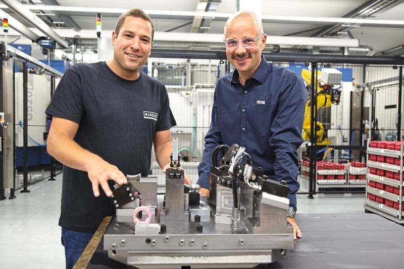 Marcel Sütterlin (li., CEO, Mandatec) und Wolfgang Ulmer (Niederlassungsleiter, Grob Schweiz) vor einer Spannvorrichtung für die lang bauenden Konsolen. Im Hintergrund die beiden flexiblen Produktionszellen. (Bild: Matthias Böhm)