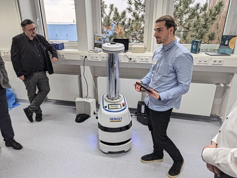 Besonders für Bio- und Pharmalabore sowie Reinräume interessant: Der Hero21 ist ein Cobot, der die Umgebung mittels UV-Bestrahlung desinfiziert. In 10 bis 15 Minuten ist ein typisches Labor komplett gereinigt. Dabei erreicht der Roboter einen Desinfektionsgrad von 99,99 %.  Sensoren erkennen, wenn ein Mensch in der Nähe ist, und pausieren die UV-Bestrahlung, bis der Hero21 wieder alleine seiner Tätigkeit nachgehen kann. Nach ca. 3,5 Stunden Dauerbetrieb muss der Roboter neu geladen werden. (Bild: VCG – Lüttmann)