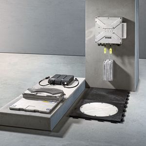 Mit Movitrans spot können die Fahrzeuge in kurzer Zeit ihre Energiespeicher aufladen und dann frei im Raum navigieren. Links im Bild: Übertragerkopf und Energiespeicher, rechts: dezentrale Einspeisung, Kompensationsbox und Verlegematte mit Feldplatte. (Bild:  SEW-Eurodrive)