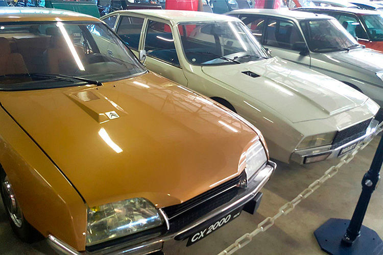 In den späten 60ern begann Citroën an einem Ersatz für die ID/DS-Baureihe zu arbeiten. Einer der Prototypen, weißlackiert, existiert noch heute, mit Armaturen aus dem SM, einem GS-Lenkrad – und steilerer Front als beim CX. 1974 kam der CX (im Bild links). (GTSpirit.de)
