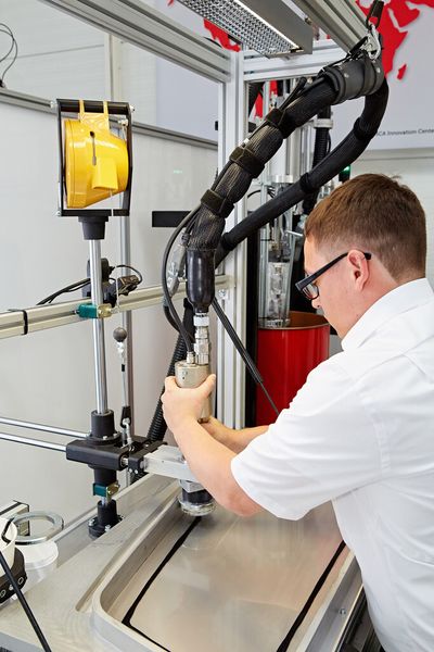 Noch ein SCA-Highlight war auf der Hausausstellung zu sehen: Ein einfacher Handlingarm entlastet den Werker bei manuellen Klebeaufgaben und macht den Prozess sicherer und effizienter. Mit der eingespannten Klebepistole arbeitet der Bediener sehr ergonomisch und schnell, wie es heißt. Das steigere die Qualität der Applikation und verringere den Materialverbrauch. (Bild: SCA)