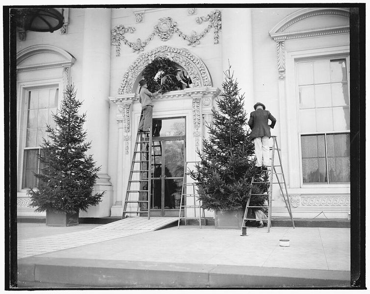 1939: Das Weiße Haus zieht sich weihnachtlich an. Washington, D.C., 19. Dezember. Arbeiter waren heute eifrig damit beschäftigt, den Weihnachtsschmuck an der Fassade des Weißen Hauses anzubringen. Die Dekoration wird an Heiligabend mit bunten Lichtern beleuchtet, wenn Präsident Roosevelt den Schalter drückt, um den Weihnachtsbaum der Gemeinde zu entzünden. (Bild: gemeinfrei)