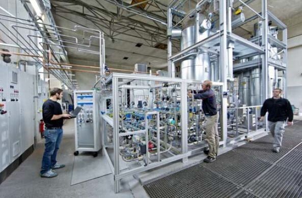 ZSW-Forscher bei der Kontrolle der Gasmischung. Im Hintergrund die Methanisierungsanlage. (Bild: ZSW)