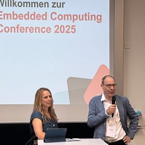 Organisator Hugo Ziegler, Sektionspräsident der swissT.net-Sektion Embedded Computing, mit der Moderatorin Denise Wenzel an der ECC2025. (Bild:  Anne Richter, VCG)