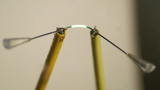 Die Forscher haben schon eine Faser von 500 Mikrometern auf 5 Millimetern zum Leuchten gebracht. Die OLEDs funktionieren auch noch, wenn die Faser gebogen wurde. (Tobias Könyves-Toth, TU Darmstadt)