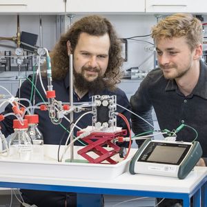 Bernhard Schmid (l.) und Maximilian Quentmeier (r.) mit dem von ihnen entwickelten Stack für die CO2-Elektrolyse.(Bild:  Forschungszentrum Jülich / Ralf-Uwe Limbach)