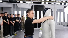 He Xiaopeng hangs an employee ID badge around the neck of the humanoid "IRON," as part of the team. (Source: Xpeng)